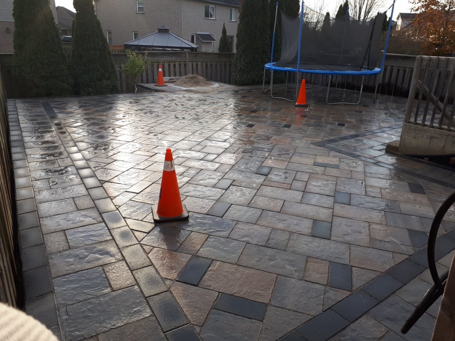 Interlocking stone patio installation in a residential backyard